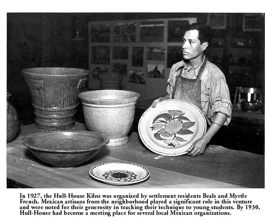 A man stands behind a table displaying handcrafted pottery, including bowls and a decorative plate, in a workshop. Text below describes Mexican artisans teaching pottery at Hull-House in 1927.