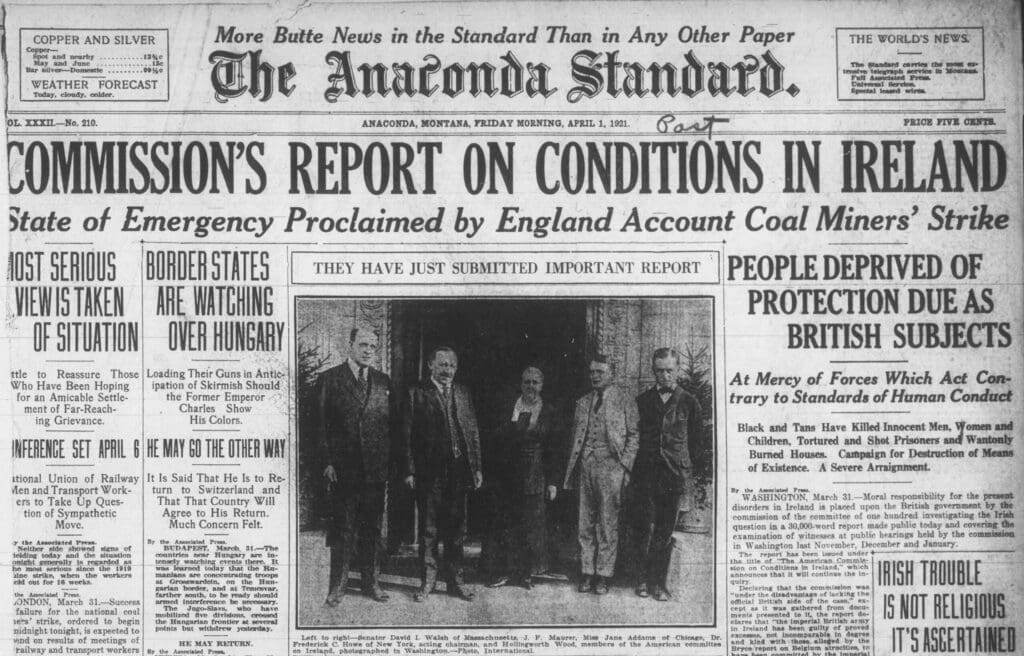Black and white 1921 newspaper front page with bold headline about Ireland, several articles, and a photo of seven men in suits standing outside a building.